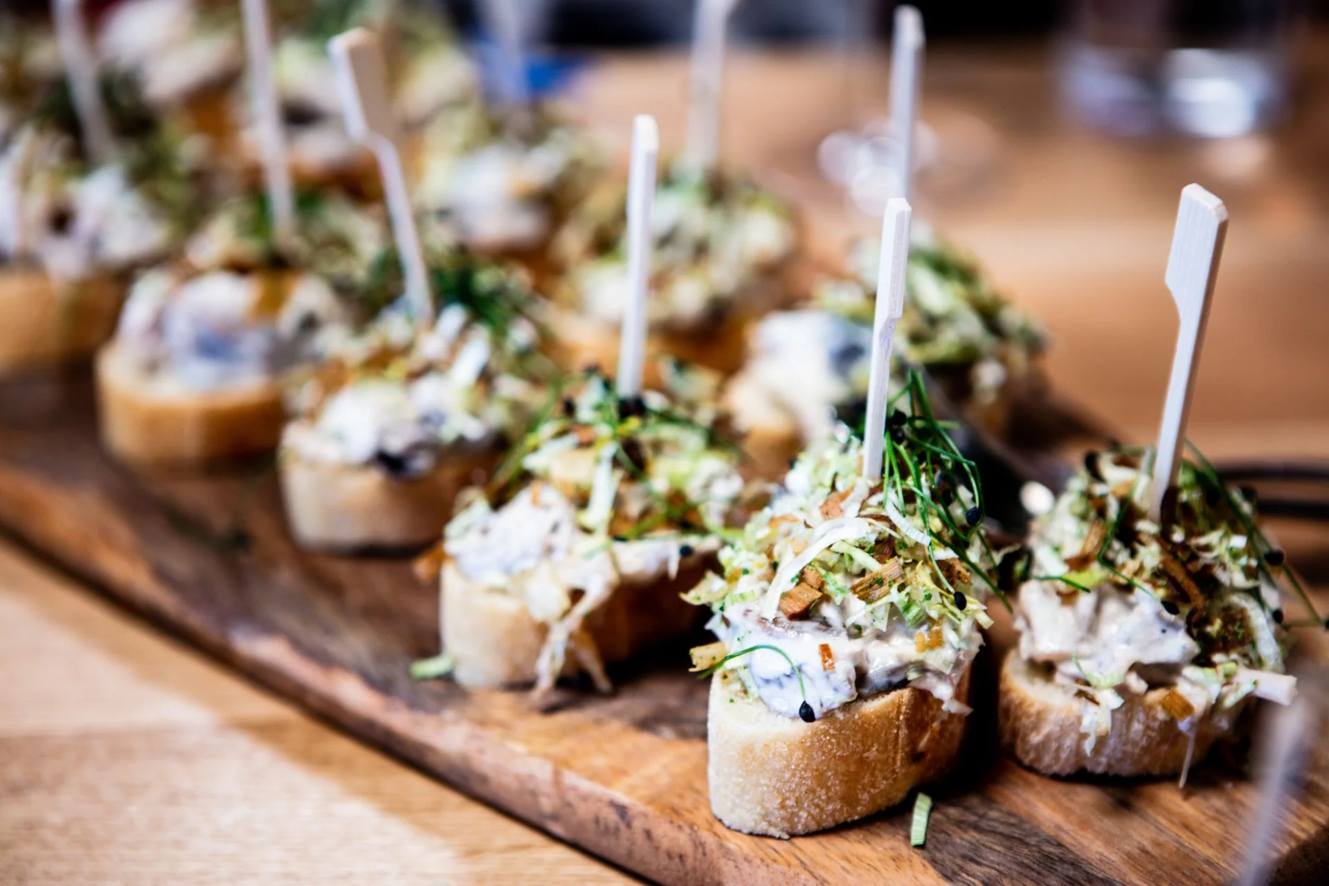 Bruschetta-style hors d'oeuvres on picks served on a wooden board